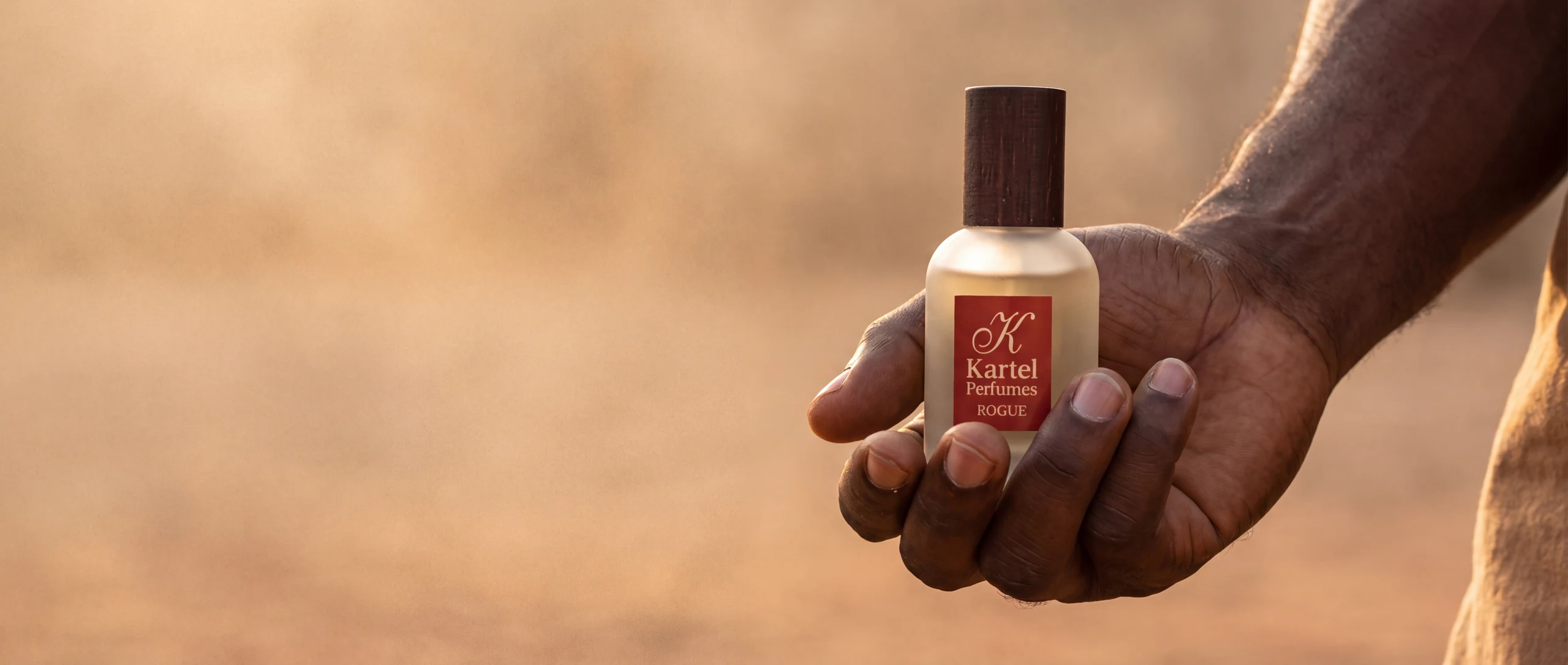 A hand holding a Rogue perfume bottle.